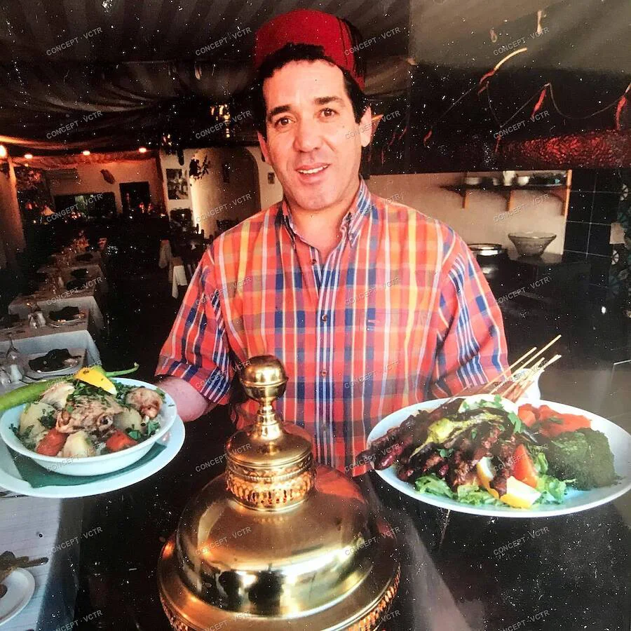 The founder of Al Casbah in 1997, holding two plates of North African food